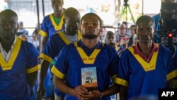 FILE - Marcel Malanga holds the Bible as he attends a trial where he is accused with others of a failed coup attempt, at Kinshasa's Ndolo prison in Kinshasa on Sept. 13, 2024.