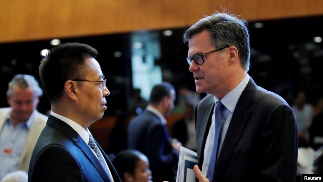 美国驻WTO大使习达难(右)在瑞士日内瓦举行的世界贸易组织会议上与中国驻WTO大使张向晨交谈。(2018年7月26日)