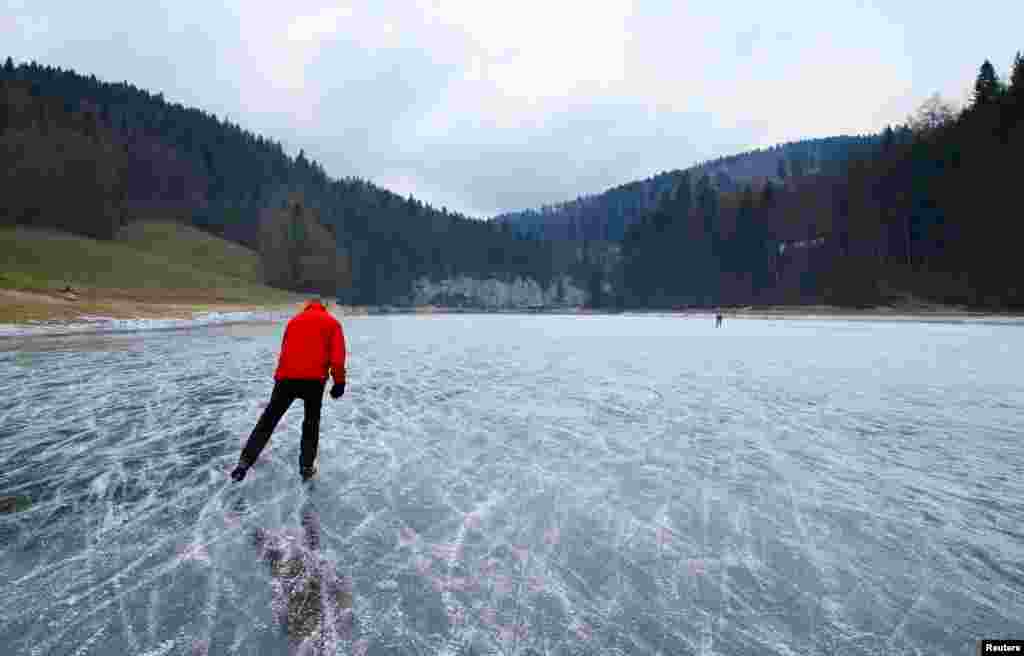 Orang-orang bermain selancar es di sungai Doubs yang membeku, di perbatasan Swiss-Perancis di Les Brenets, Swiss.
