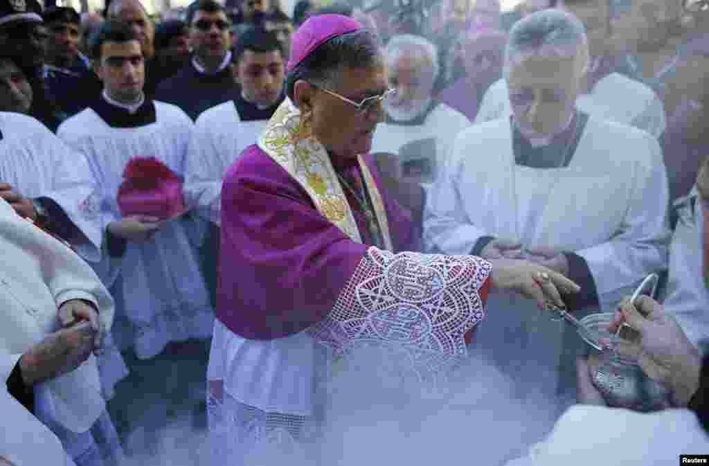 Patriark Latin atau Uskup Agung Yerusalem Fouad Twal (tengah) bersiap memberkati massa di luar Gereja Nativity (24/12).