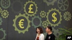 Mural di sebuah bank bersimbol mata uang berbagai negara, termasuk dolar (Amerika) dan yuan (China), di Beijing, China, 7 Juli 2018. (Foto: dok). 