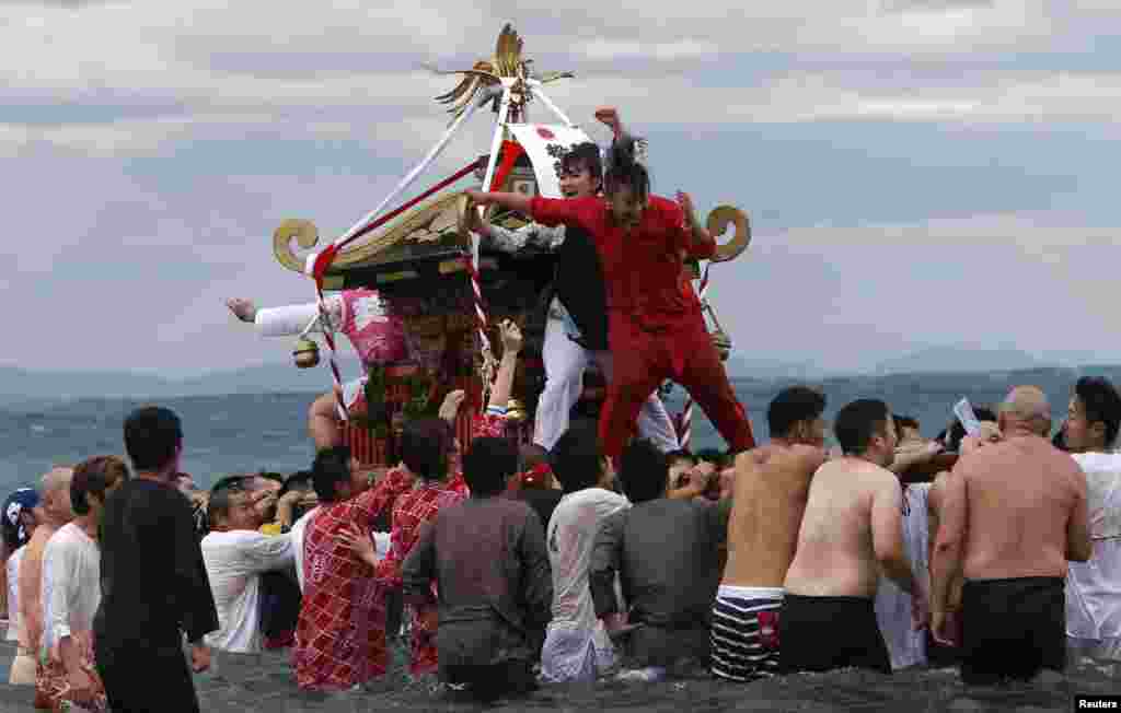 Women riding on a &quot;mikoshi&quot; or portable shrine cheer as people carry the shrine into the sea during a festival to wish for calm waters in the ocean and good fortune in the new year in Oiso, west of Tokyo, Japan.