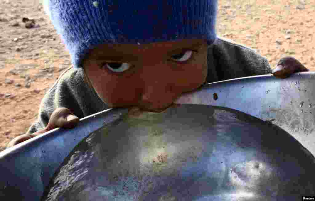 A stateless Arab boy from an ethnic group known as Bedoon, who are believed to be descendants of nomadic Bedouins, drinks water from a pot in a desert west of Al-Jawf region, Saudi Arabia.