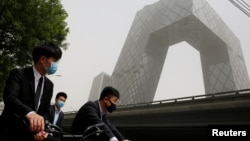 Orang-orang mengenakan masker di dekat kantor pusat China Central Television (CCTV) di Beijing, China, 4 Mei 2017. (Foto: Reuters)