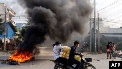 Motorists pass a burning barricade during a crackdown by security forces on demonstrations by protesters against the military coup in Mandalay, March 22, 2021, in this photo taken and received courtesy of an anonymous source.