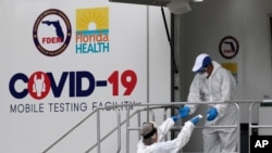 Health care workers work at a walk-up COVID-19 testing site during the coronavirus pandemic, Friday, July 17, 2020, in Miami Beach, Fla.