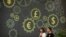 FILE - People walk past a mural on a bank showing symbols for American, Chinese and other world currencies in Beijing, July 7, 2018.