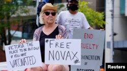 A protestor holds signs outside the Park Hotel, where Serbian tennis player Novak Djokovic is believed to be held, in Melbourne, Australia January 6, 2022. 