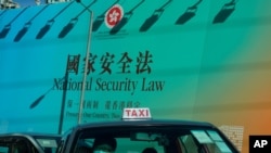 A taxi drives past a big banner featuring the Hong Kong National Security Law in Hong Kong, June 29, 2020. 