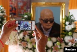 A woman uses a smart phone to take a picture of a portrait of the former chief ideologist and 'Brother Number Two' of Cambodia's Khmer Rouge Nuon Chea during his funeral in Pailin province, Cambodia, August 6, 2019.