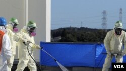 Para pekerja membersihkan atap kantor Okuma dari kontaminasi dekat pembangkit nuklir Fukushima Daiichi (4/12).