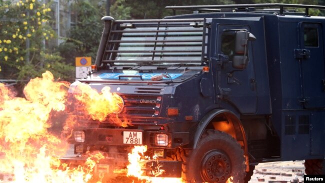 香港抗议者和警方星期天（11月17日）在理工大学外爆发激烈冲突。一辆警方车辆正在穿过大火。