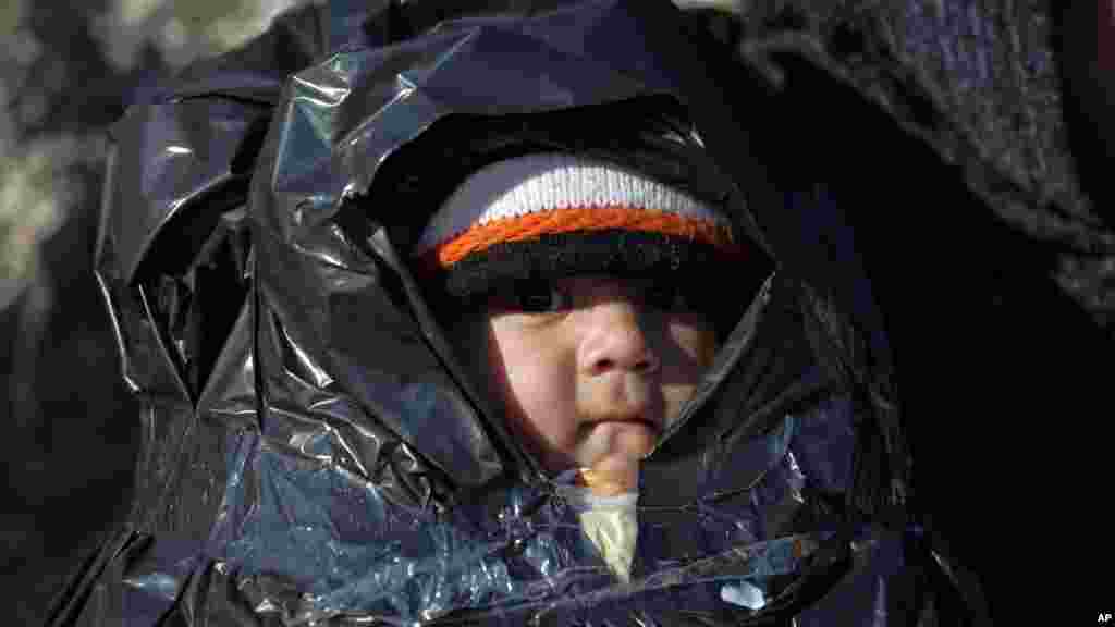 Couvert d&rsquo;un plastique, un enfant voyage avec d&rsquo;autres migrants à bord d&rsquo;un canot à l&#39;île grecque de Chios, en Turquie, 4 novembre 2015.&nbsp;