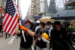 A protester carries a U.S. flag as they march through the Mong Kok neighborhood during a demonstration in Hong Kong, Saturday, Aug. 3, 2019.