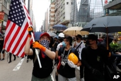 A protester carries a U.S. flag as they march through the Mong Kok neighborhood during a demonstration in Hong Kong, Saturday, Aug. 3, 2019.
