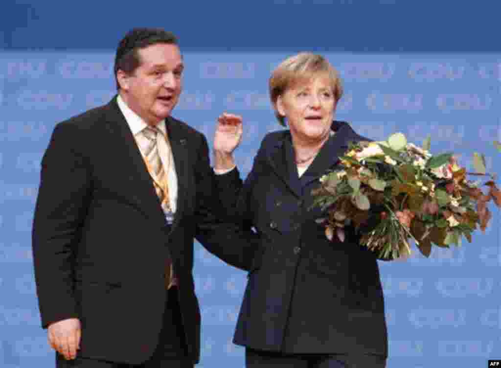 German Chancellor Angela Merkel has received flowers by Baden-Wuerttemberg state governor Stefan Mappus after her reelection as CDY arty board during a party meeting of Christian Democratic Union in Karlsruhe, Germany, Monday, Nov. 15, 2010. (AP Photo/Mic