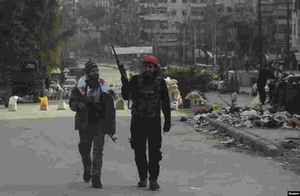 Syrian rebel fighters hold their weapons as they walk along a street in Aleppo's Salaheddine neighborhood, Jan. 10, 2014.