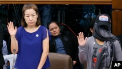 Choi Kyung-jin, left, the widow of South Korean businessman Jee Ick-joo take their oaths at the start of the Philippine Senate probe of the killing.