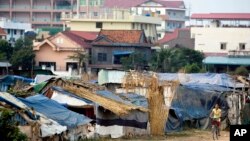 A young Cambodian woman rides a bike near slum homes on the outskirts of Phnom Penh, file photo. 