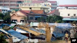 A young Cambodian woman rides near slum homes on the outskirts of Phnom Penh, file photo. 