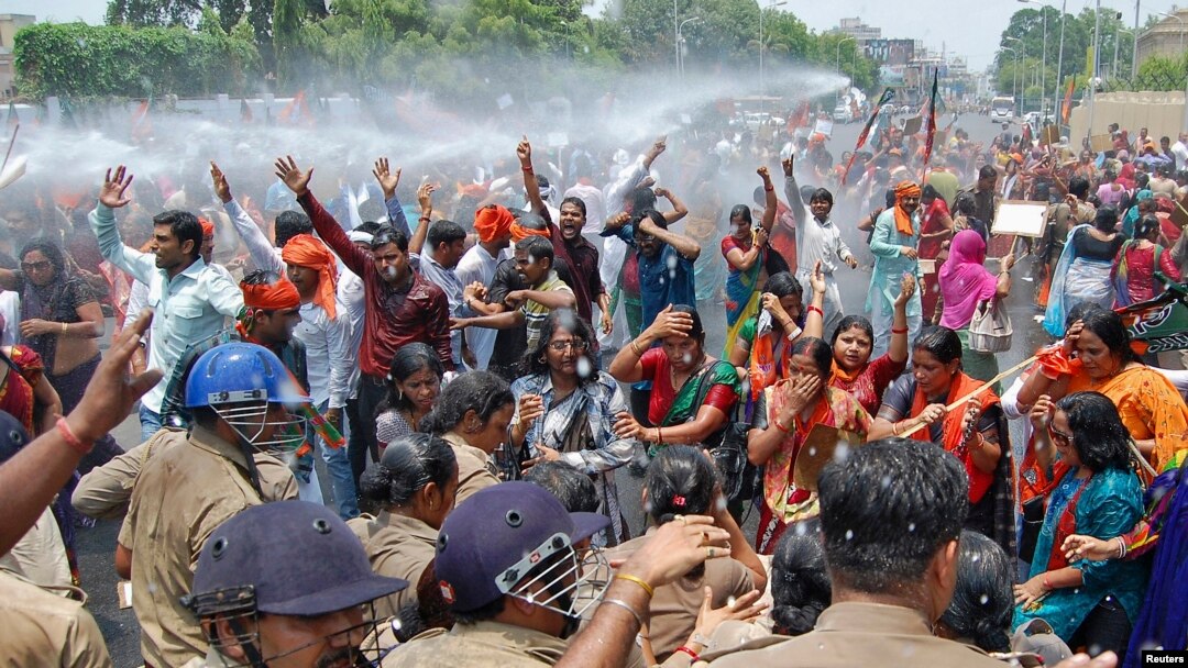 Pendukung Partai Bharatiya Janata Party (BJP) meneriakkan slogan saat polisi menembakkan meriam air untuk menghentikan perjalanan mereka menuju kantor pemimpin negara bagian Uttar Pradesh, Senin (2/5), memprotes perkosaan beramai-ramai di wilayah ini. 