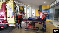 英国两名救护人员在收治了一名被确诊为新冠病毒患者的 Son Espases 大学医院外做救护的准备工作。（2020年2月9日）