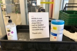 In this March 29, 2020, photo, a sign posted at an entrance to a 365 Whole Foods store advises customers not to use their own bags while shopping in Lake Oswego, Ore.