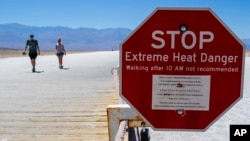 FILE - A sign warns people of extreme heat in multiple languages on Tuesday, July 11, 2023, in Death Valley National Park, Calif. July is the hottest month at the park with an average high of 116 degrees (46.5 Celsius).