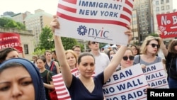 Protesters hold signs against U.S. President Donald Trump's limited travel ban, approved by the U.S. Supreme Court, in New York City, U.S. on June 29, 2017. REUTERS/Joe Penney/File Photo