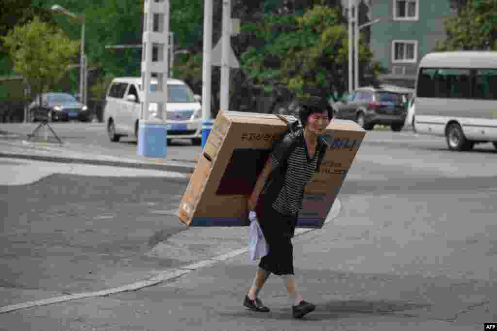 A woman carries a flat-screen television on her back in Pyongyang, North Korea.