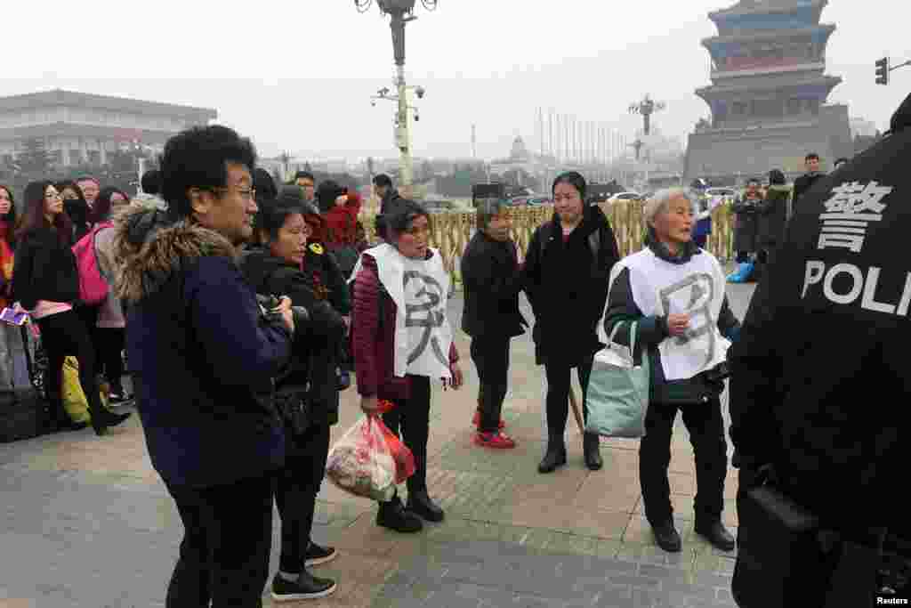 2018年3月3日，中国人民政治协商会议在北京开幕之前，警察在天安门广场旁边接触上访的妇女请愿者。身披&ldquo;冤&rdquo;字的上访者后来被带走。