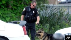 A police K-9 team takes a break in the search for suspects in the shooting of a police officer in Fox Lake, Ill., Sept. 1, 2015.