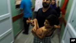 A Palestinian man carries a child, wounded in an Israeli strike on a compound housing a U.N. school in Beit Hanoun, in the northern Gaza Strip, into the emergency room of the Kamal Adwan hospital in Beit Lahiya, July 24, 2014.