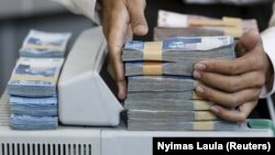 Seorang teller menumpuk Rupiah Indonesia di konter mata uang di dalam money changer di Jakarta. (Foto: Reuters/Nyimas Laula)