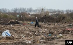 FILE - A man walks among remains of taken down shelters during the dismantling of the southern part of the so-called "Jungle" migrant camp in Calais, northern France, March 10, 2016.