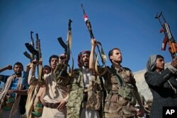 FILE - Tribesmen loyal to Houthi rebels hold up their weapons as they attend a gathering to show their support for the ongoing peace talks being held in Sweden, in Sanaa, Yemen, Dec. 13, 2018.
