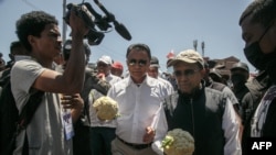 FILE - Former Madagascar president and member of the opposition Marc Ravalomanana (2nd L) and former Madagascar president and opposition figure Hery Rajaonarimampianina (2nd R) hold a colliflower, a vegetable that become a symbol of police repression, as they jo