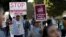 FILE - People hold signs as they gather outside a Federal Building while protesting against Immigration and Customs Enforcement (ICE) raids on Central American refugees in Los Angeles, California, Jan. 26, 2016.