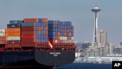 FILE - In this Feb. 15, 2015, file photo, the Space Needle towers in the background beyond a container ship anchored in Elliott Bay near downtown Seattle.