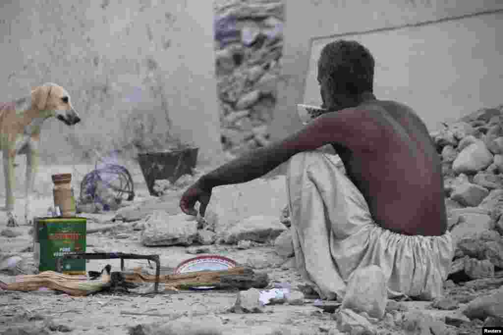 Seorang penyintas duduk dan minum teh di tengah puing-puing rumahnya yang roboh akibat gempa. (Reuters/Sallah Jan)