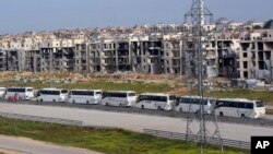 FILE - In this photo released by the Syrian official news agency SANA, buses carry Syrian citizens, who evacuated from the two pro-government villages of Foua and Kfarya, arrive at a handover point between the two sides on the outskirts of Aleppo, Syria, April 21, 2017. 