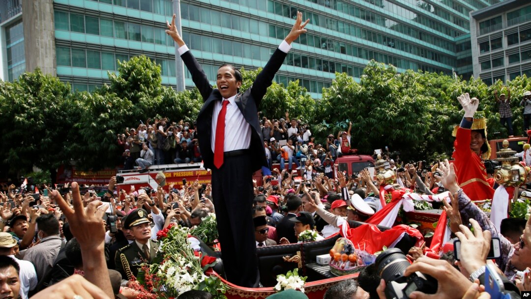 Presiden Joko Widodo memberikan salam kepada seluruh masyarakat yang memadati jalanan Jakarta, dalam pawai menuju Monas, seusai pelantikannya sebagai Presiden (20/10).