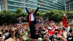 Presiden Joko Widodo memberikan salam kepada seluruh masyarakat yang memadati jalanan Jakarta, dalam pawai menuju Monas, seusai pelantikannya sebagai Presiden (20/10).