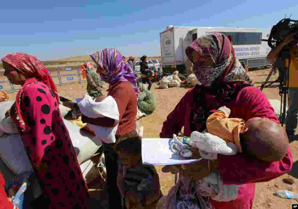 Narin Mustafa, 26 (center) holds her 10-day-old baby girl as thousands of new Syrian refugees from Kobani arrive at the Turkey-Syria border crossing of Yumurtalik near Suruc, Turkey, Oct. 1, 2014. 