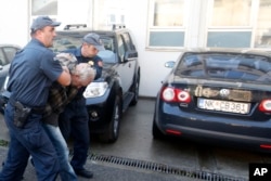 FILE - Montenegrin police officers escort a suspect in Podgorica, Oct. 16, 2016. In all, 20 suspects linked to a coup plot aimed at derailing the Balkan nation's bid to join NATO were arrested ahead of Montenegrin elections.