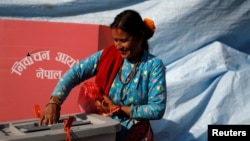 Seorang wanita tersenyum saat memasukkan surat suaranya ke dalam kotak suara pada pemilihan parlemen dan provinsi di Distrik Sindhupalchok, Nepal, 26 November 2017. (Foto: dok).