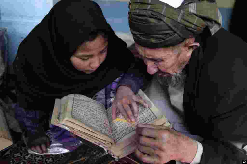 An Afghan teacher teaches a girl how to read the Quran, Islam&#39;s holy book, at a local Madrassa, or seminary, in Kabul, Afghanistan.