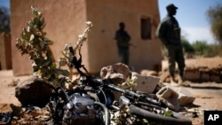 Malian soldiers stand by a motorcycle used by a suicide bomber at the entrance of Gao, northern Mali, Feb. 8, 2013.