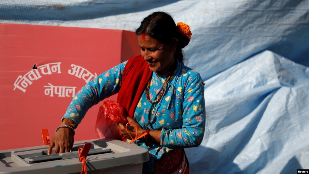 Seorang wanita tersenyum saat memasukkan surat suaranya ke dalam kotak suara pada pemilihan parlemen dan provinsi di Distrik Sindhupalchok, Nepal, 26 November 2017. (Foto: dok).