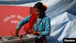 A woman smiles as she cast her vote on a ballot box during the parliamentary and provincial elections in Sindhupalchok District, Nepal, Nov. 26, 2017.